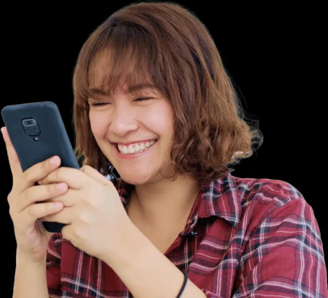 A woman smiling while looking at her cell phone