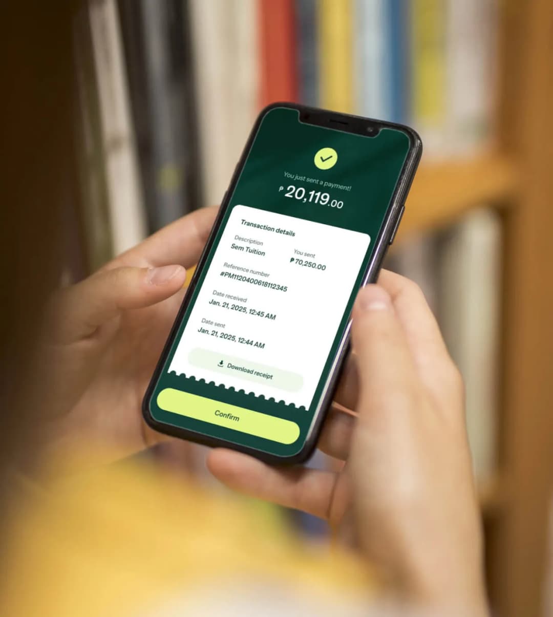 A person holding a cell phone in front of a bookshelf