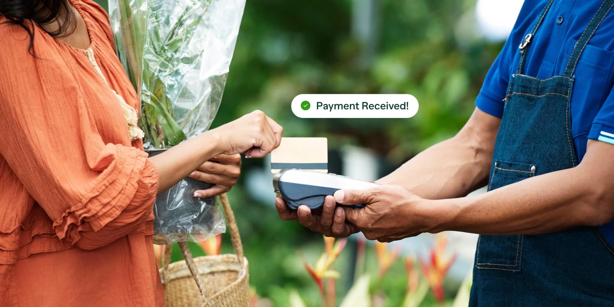 A customer in an orange dress makes a contactless payment using a credit card while purchasing flowers from a vendor in a blue apron, with a 'Payment Received!' confirmation displayed.