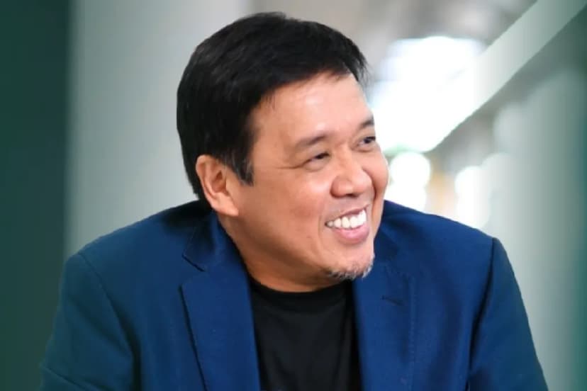 A man in a blue coat smiles at the camera.